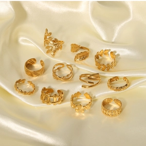 Flat lay of 11-piece 18k gold plated stainless steel floral and leaf ring set on silk