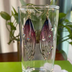Macro detail of long cicada wing drop earrings with purple gradients and crystals