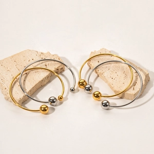 Close-up of minimalist gold and silver open ball bracelets on natural stone props
