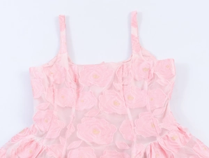 Vue détaillée du tissu jacquard rose à motif de roses et des fines bretelles de la robe