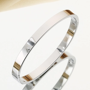 Detailed close-up of polished silver stainless steel oval bangle with spring clasp mechanism
