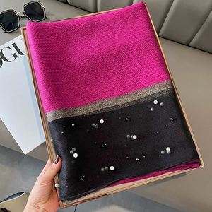 Close-up of pink and black knit scarf with faux pearls and golden lurex details