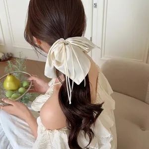 Élastique nœud en satin crème avec perle centrale porté sur une coiffure élégante