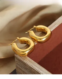 Detailed close-up of gold-plated U-shaped earrings with a polished mirror finish on silk
