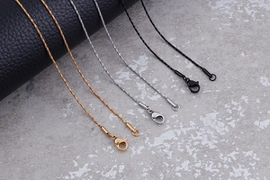 Detailed close-up of metallic necklaces in gold, silver, and black with lobster clasps