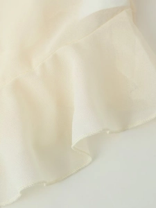 Dettaglio ravvicinato dei bordi a balze e della trama in chiffon di un set coordinato top