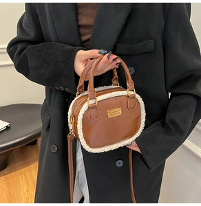 Macro detail of brown leather pillow bag with white faux fur trim and gold metal logo plaque