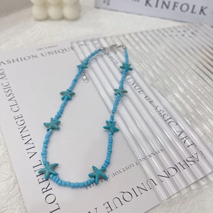 Detailed close-up of blue seed bead necklace with starfish pendants on a flat lay background