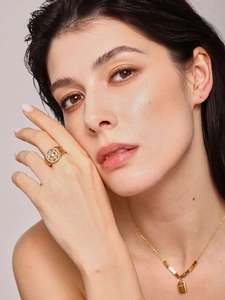 Detailed close-up of hollow geometric gold ring with inlaid zircon on female model