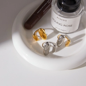 Nahaufnahme minimalistischer Kapsel-Ringe in Gold und Silber auf einer Keramikschale