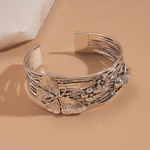 Detailed macro shot of vintage silver cuff bracelet with embossed butterfly and floral patterns