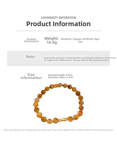 Détail d'un bracelet de perles avec un charm poisson doré et pierres oeil de tigre