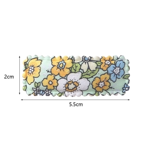 Detail showing 5.5cm floral fabric hair clip with embroidery on soft green base