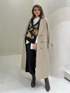 Minimalist beige wool coat layered with a V-neck jacquard vest and white shirt