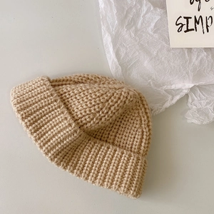 Primer plano del gorro de punto beige con dobladillo sobre un fondo blanco minimalista