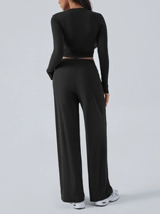 Women's black long sleeve crop top and wide leg pants yoga set shown from the back