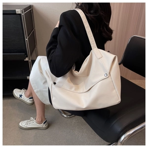 Close-up of minimalist beige tote bag with pebbled leather texture and wide shoulder strap