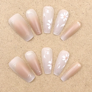 Coffin press-on nails featuring nude pink gradient and white floral daisy patterns