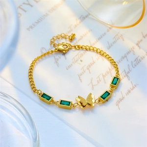 Gold titanium bracelet featuring green emerald-cut stones and a delicate butterfly charm