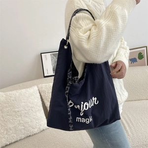 Detail of navy blue canvas tote bag with Bonjour magic text and leopard print strap