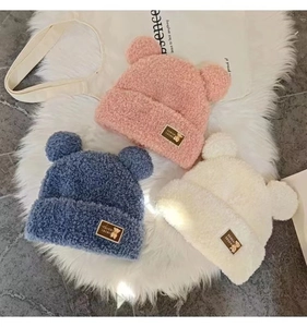 Flat lay detail showing plush bear ear hats in pink, blue, and white soft fleece