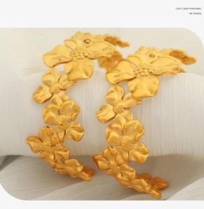 Macro shot of matte gold camellia C-shaped earrings with detailed petal texture