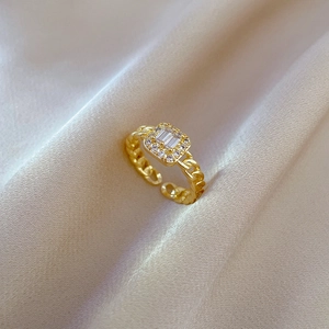 Close-up of gold plated square zircon ring on beige fabric with an adjustable band