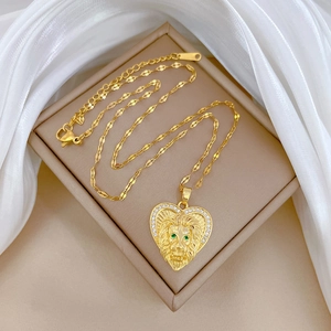 Gold titanium lion heart necklace with green eyes and sparkling zircons in a beige jewelry box