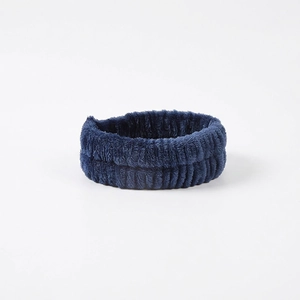 Close-up of a navy blue coral fleece headband showing soft texture and elastic stretch