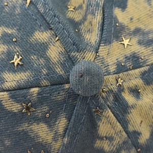 Detailopname van baseballpet met sterrenprint, denim textuur en gouden sterdetails