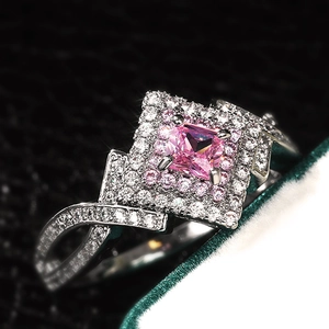 Macro shot of square pink gemstone ring with double halo and twisted pavé band