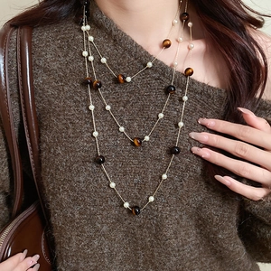 Multi-layer necklace with pearls and tiger eye stone on brown tweed sweater
