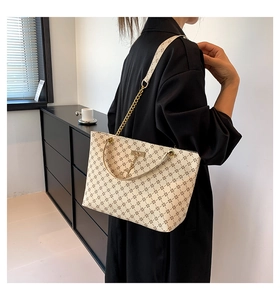 Dettaglio della borsa tote beige con stampe floreali e tracolla a catena in metallo