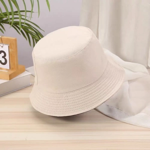 Detail of a beige cotton canvas bucket hat on a wooden surface with a soft sunlit background