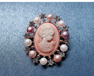 Detail of pink Victorian cameo brooch with pearls and rhinestones on blue silk fabric