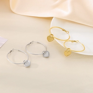 Detail of twisted gold and silver hoop earrings with heart charms on silk and ceramic