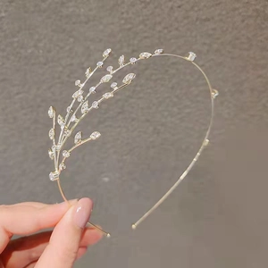 Elegant gold metal headband featuring clear leaf rhinestones in a branch design