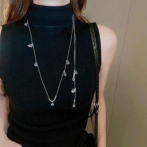 Long collier argenté à perles et pendentifs en zircone sur col roulé noir