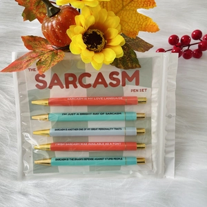 Das Sarcasm Pen Set mit 5 bunten Kugelschreibern auf weißem Plüschhintergrund