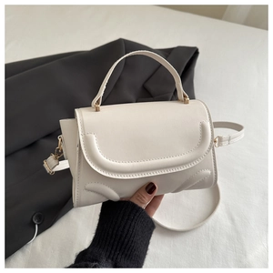 Detail of white PU leather crossbody bag with U-shaped stitching and gold hardware