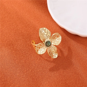 Detailed macro of a gold flower ring with textured petals and a green stone center