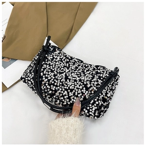 Detailed close-up of sparkling silver sequins on a stylish black baguette shoulder bag