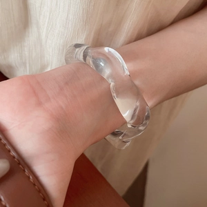 Close-up of a clear acrylic wavy bangle with irregular design worn on a wrist