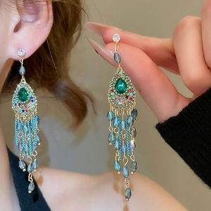 Detail of vintage gold tassel earrings with emerald crystal and colorful rhinestone accents