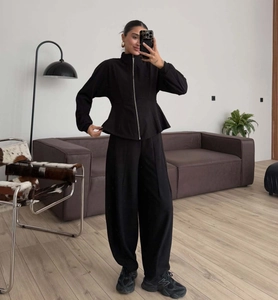 Detail of slim-fit black zip-up sweatshirt with peplum hem and matching high-waist pants