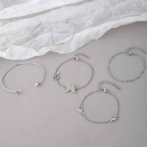 Close-up of 5-piece silver bracelet set featuring butterfly charm and star bangles