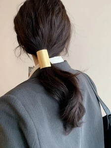 Polished gold metal ponytail cuff hair clip shown on an elegant low ponytail hairstyle