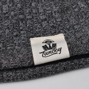 Macro detail of melange knit fabric showing gray texture and Tunboy brand woven label