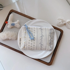 Nahaufnahme einer geblümten Baumwolltasche mit blauem Reißverschluss auf einem Tablett