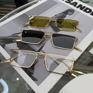 Rectangular gold metal sunglasses with colored lenses on a fashion magazine